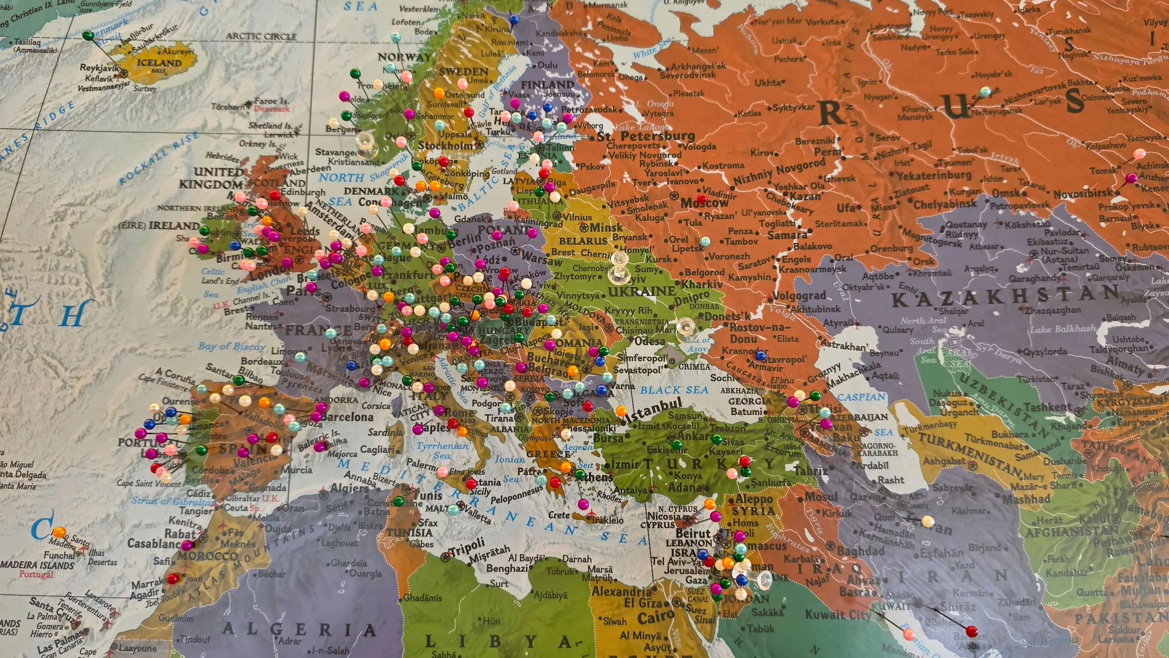 Close-up of a wall map of Europe and the Middle East densely studded with coloured pins; most of them in Central Europe, Spain, Britain and Scandinavia